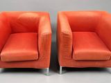 pair of orange leather lounge chairs with chrome legs