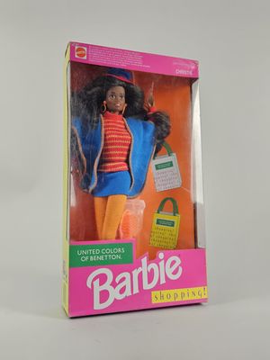 une poupée Barbie dans une boîte, posée sur une surface blanche, avec un fond blanc