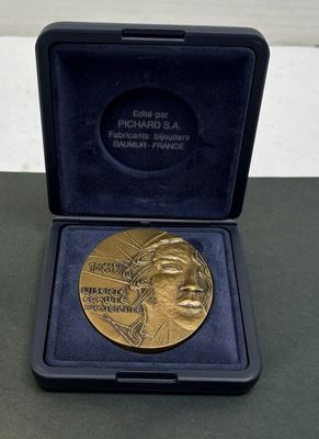 une médaille d'or dans un écrin noir posé sur une table