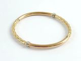 a close up of a gold bang bracelet on a white background