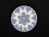 assiette bleue et blanche ornée d'un motif floral sur fond noir