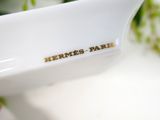 a white bowl with a name on it sitting next to a plant
