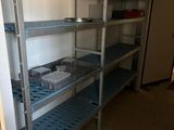 a metal shelf in a kitchen with dishes and pans on it