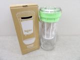 un gobelet en verre avec un couvercle vert à côté d'une boîte en carton
