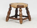 an old wooden stool with a roped seat on top of it