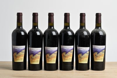 six bottles of wine are lined up on a wooden table