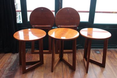 trois tabourets en bois placés les uns à côté des autres sur un plancher en bois