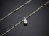 un pendentif orné d'un seul diamant est suspendu à une chaîne posée sur une surface noire