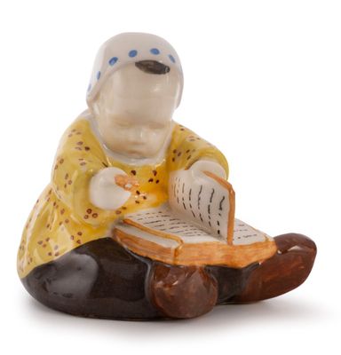 a figurine of a woman sitting on a rock reading a book