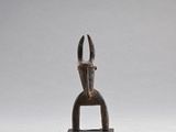 une petite sculpture en bois représentant une main tenant une paire de ciseaux