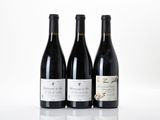 three bottles of red wine are lined up on a white surface
