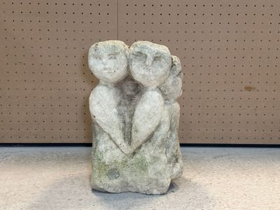 une sculpture en pierre représentant deux personnes se tenant la main, allongées par terre