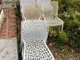 four white chairs sitting in front of a brick wall