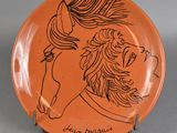 une assiette orange sur laquelle est dessiné un cheval