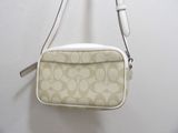 beige and white purse hanging on a wall with a white background