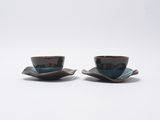 deux tasses posées sur une soucoupe, sur une surface blanche