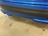 the rear end of a blue car with a sticker on it ' s bumper