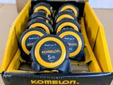 une boîte contenant un mètre ruban Komelon, présentée dans un carton