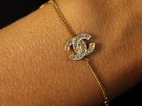 a close up of a woman ' s arm wearing a gold bracelet with a diamond heart charm