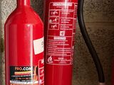 fire extinguisors are lined up on a shelf next to a brick wall