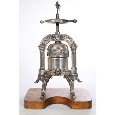 une cafetière à piston ancienne en métal argenté, posée sur un socle en bois