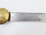 a close up of a knife with a gold handle on a white surface