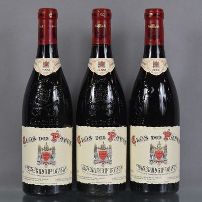 trois bouteilles de vin rouge sont posées sur une table en verre