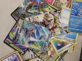 une pile de cartes Pokémon posée par terre à côté d'un ordinateur portable