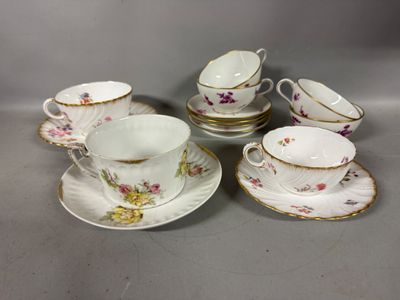 quatre tasses et soucoupes ornées de motifs floraux sont posées sur une table