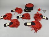 six red pom poms and a hat on a table