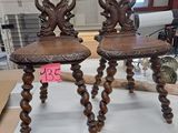 une paire de chaises anciennes en bois sculpté exposées dans un magasin