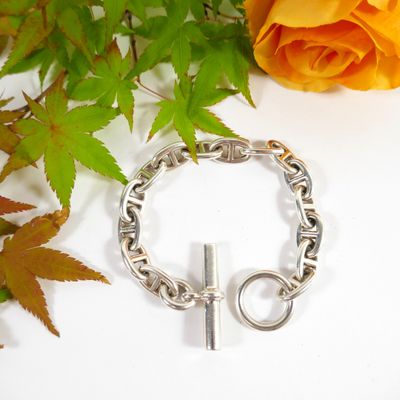 a silver bracelet with a cross on it next to a rose