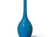 un vase bleu posé sur une surface blanche, avec un fond blanc