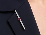 a close up of a woman ' s lapel with a pink stone in it