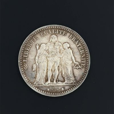 an old silver coin on a black surface with a black background
