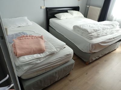 deux lits dans une petite chambre, recouverts de draps blancs