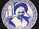 une assiette bleue et blanche sur laquelle est représentée une vieille femme