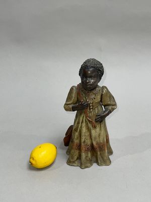 a small figurine of a woman holding a bag next to a lemon