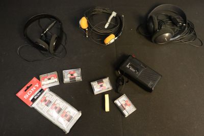 a black table with headphones, a charger, and other electronics on it