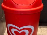 a red trash can with a heart sticker on it