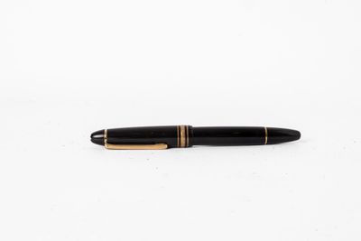 un stylo noir et or posé sur une surface blanche