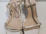 gold and white high heeled sandals on a white surface