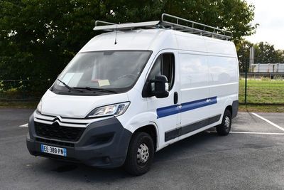 une camionnette blanche garée sur un parking avec des arbres en arrière-plan