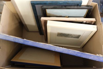 a cardboard box full of framed pictures and other items