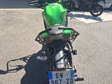 une moto verte garée sur un parking à côté d'un immeuble