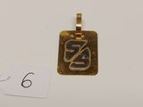 un pendentif en or sur lequel est gravée la lettre z