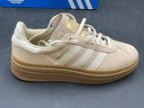 beige and white adidas sneakers on display in front of a blue box