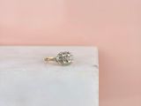 un gros plan d'une bague de fiançailles en diamant posée sur un bloc de marbre