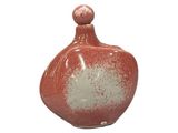a small red and white vase with a white top