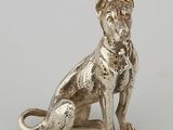 an antique silver dog figurine sitting on a white surface